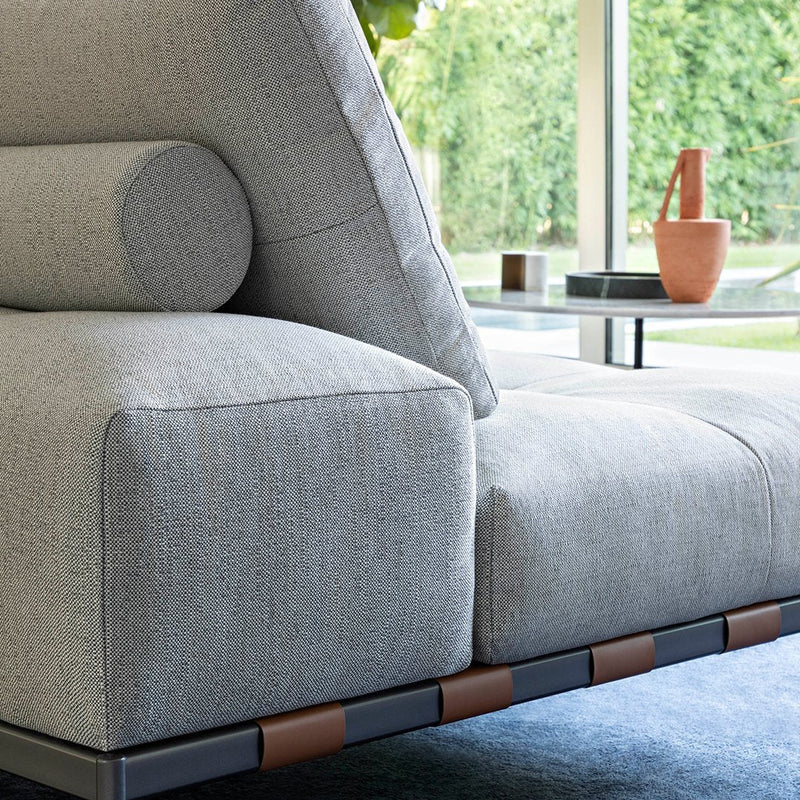 Light gray textured sofa with a cylindrical cushion, featuring a sleek black and brown frame. Modern, minimalist design.