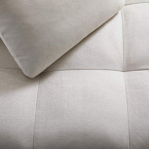 Soft beige fabric with a square quilted pattern and a smooth, light-colored pillow.