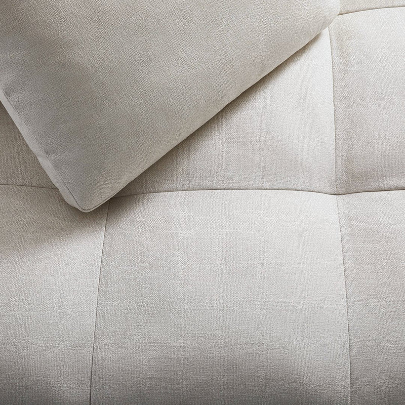 Soft beige fabric with a square quilted pattern and a smooth, light-colored pillow.
