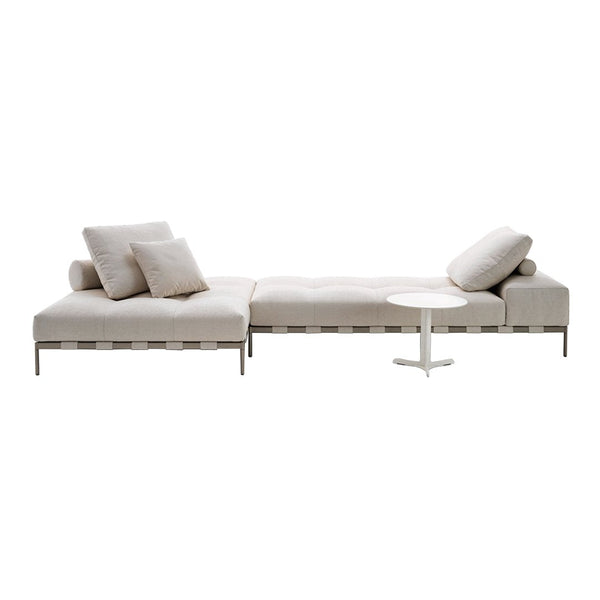 "Light beige sectional sofa with soft cushions and sleek, modern design, complemented by a simple white side table."