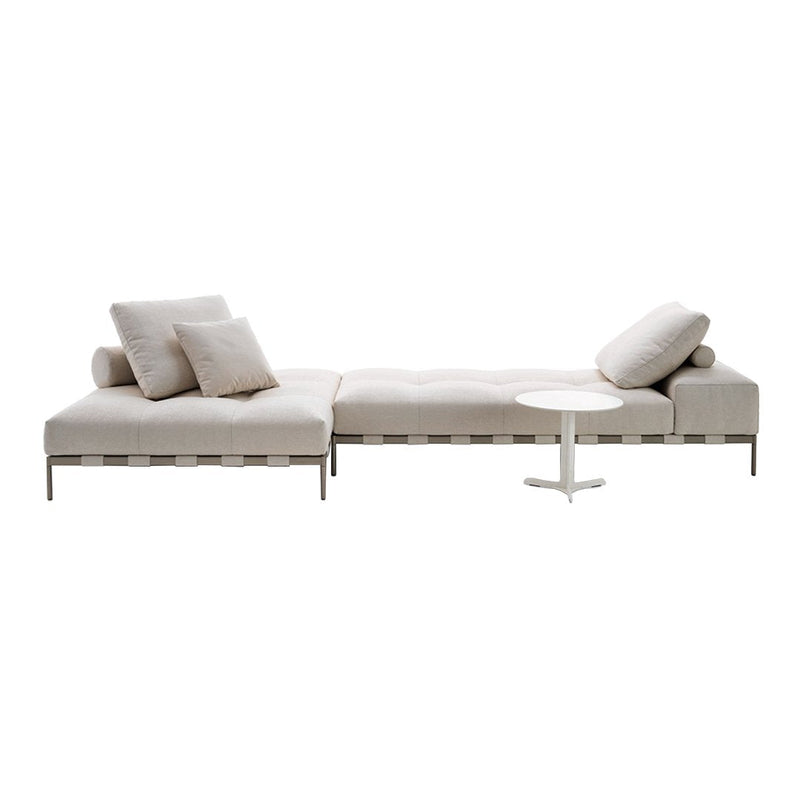 "Light beige sectional sofa with soft cushions and sleek, modern design, complemented by a simple white side table."
