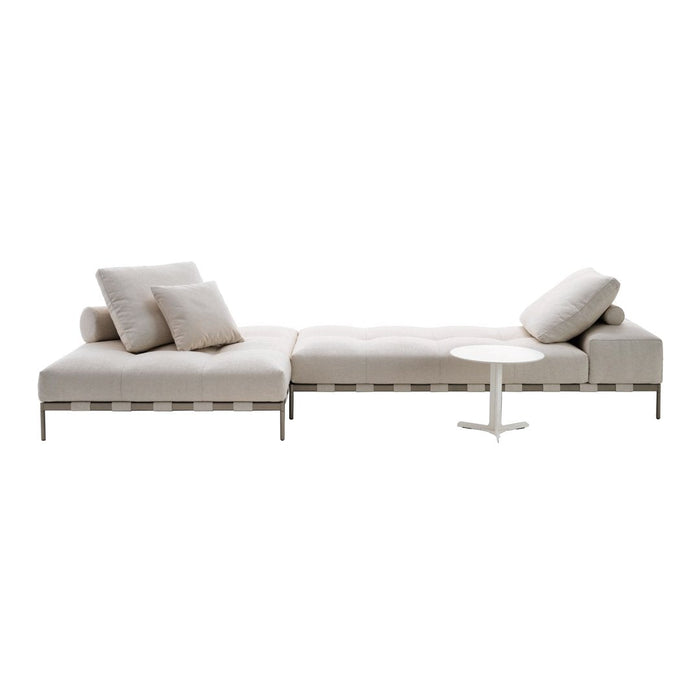 Light beige sectional sofa with subtle texture, complemented by soft neutral throw pillows and a sleek white side table.