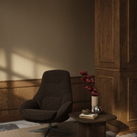 Cozy brown armchair with smooth fabric, paired with a rustic wooden table and deep burgundy flower accents.