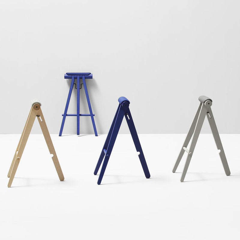 "Set of three folding stools in natural wood, navy blue, and light gray against a minimalist white background."