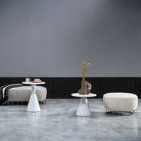 Modern white furniture with circular and geometric patterns, set against a gray backdrop and black grid wall.