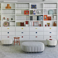 "Modern storage unit with colorful drawer knobs, featuring white shelves and playful decor in red, blue, and yellow patterns."