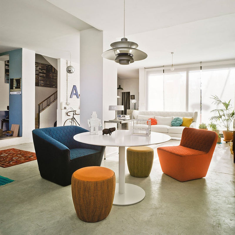 Colorful modern seating in blue, orange, and brown, paired with a white round table in a stylish living space.