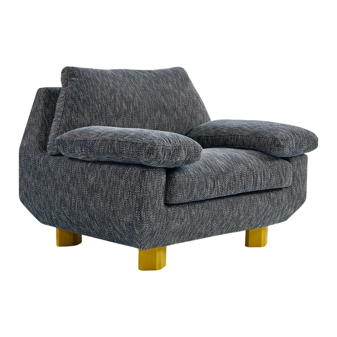 Gray textured armchair with plush cushions and golden wooden legs. Ideal for modern home decor.