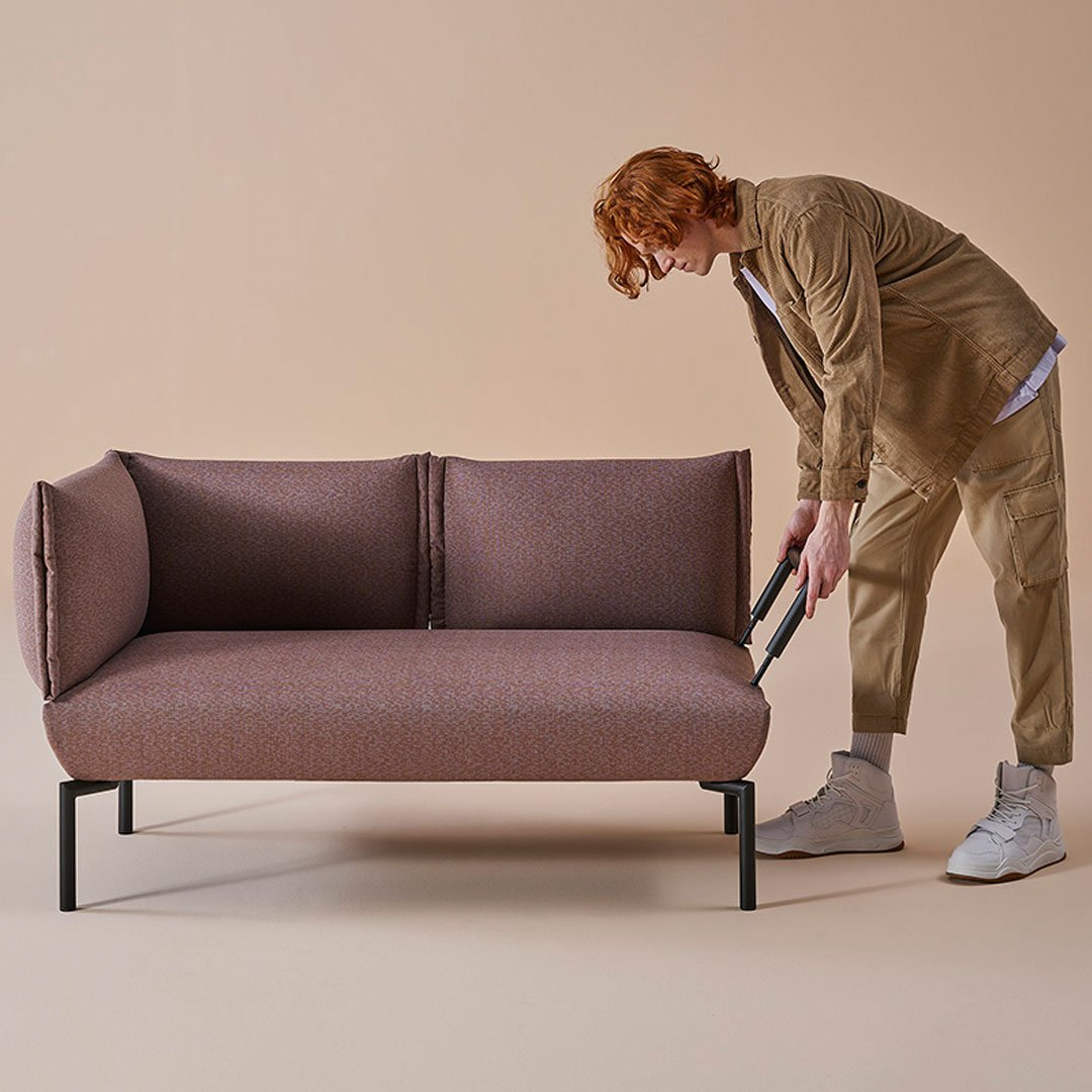 Contemporary two-tone sofa in muted mauve and gray fabric with sleek black legs, perfect for modern interiors.