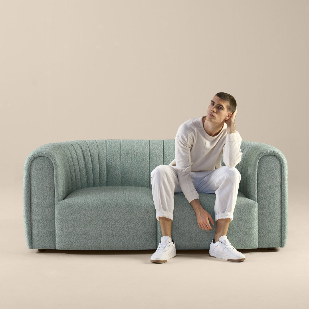 Contemporary teal sofa with ribbed texture against a soft beige background. Ideal for stylish living spaces.
