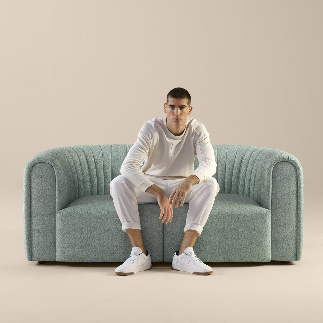 Light teal upholstered sofa with ribbed pattern, set against a neutral beige background.