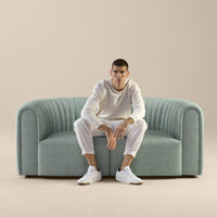 Light teal upholstered sofa with ribbed pattern, set against a neutral beige background.