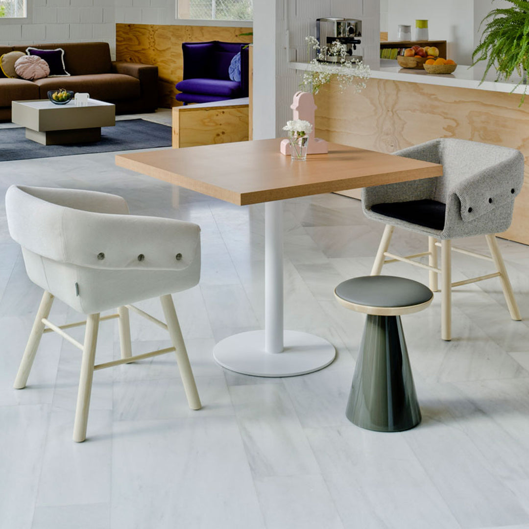 Modern dining set featuring gray and white chairs with wooden accents, a light wood table, and a green stool.