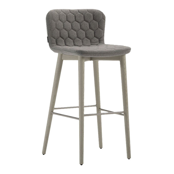 Gray upholstered bar stool with a hexagonal quilted pattern and light beige wooden legs. Modern and stylish accent piece.