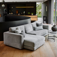 Gray sectional sofa with soft texture, featuring matching decorative pillows and set against a modern black and wood interior.