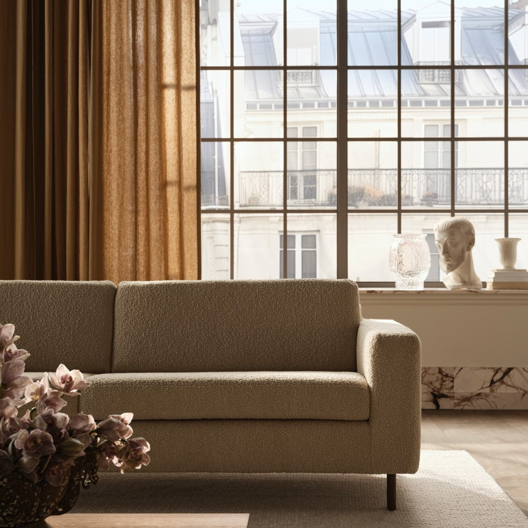 Neutral beige sofa with soft texture, complemented by warm golden curtains and a light-colored rug.