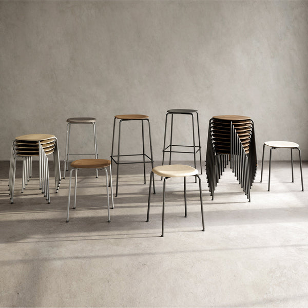 Various stacked and standalone stools in black, white, and natural wood tones on a neutral gray background.