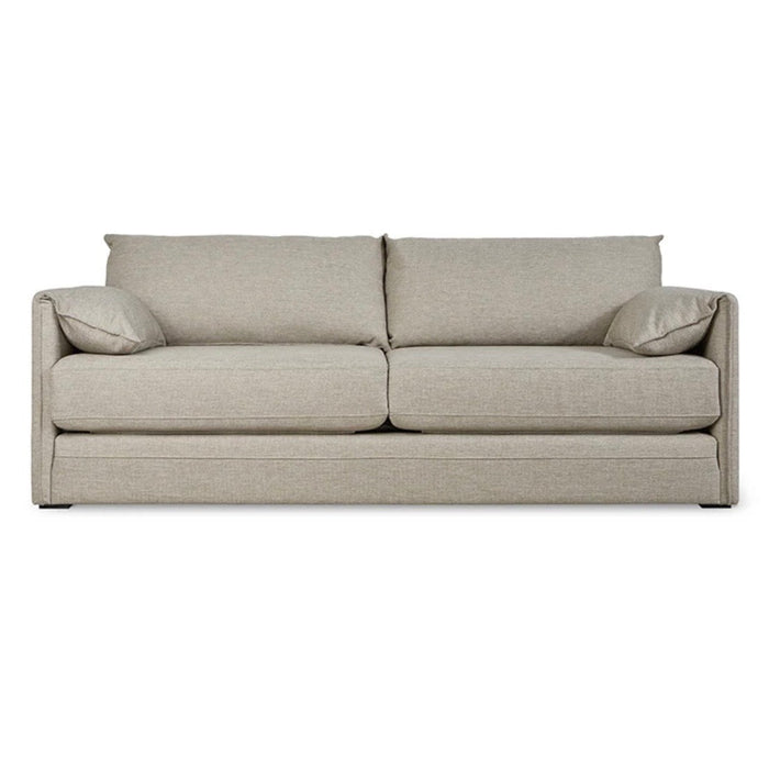 Light beige upholstered sofa with minimalist design and plush back cushions, featuring a smooth, textured fabric.