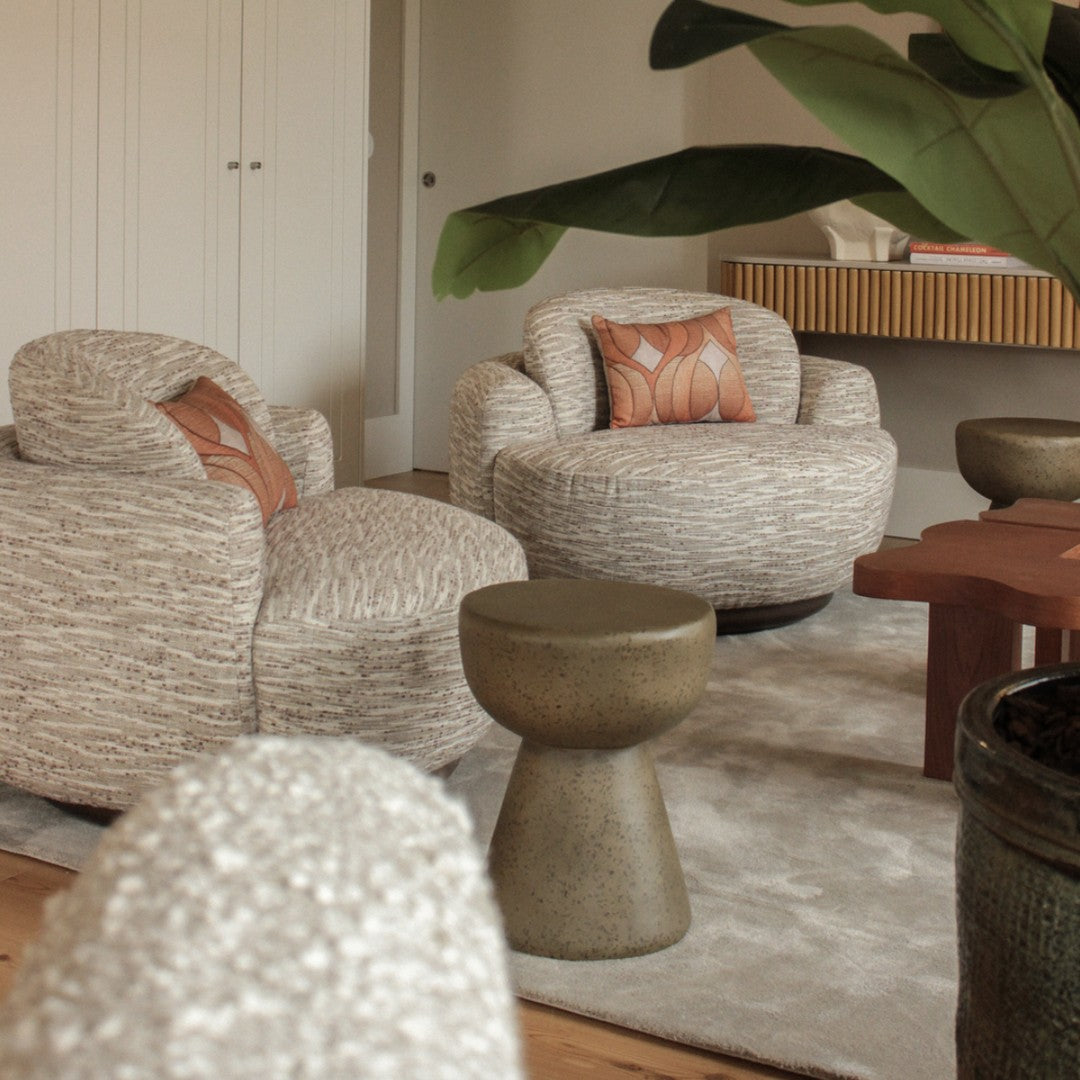 "Neutral textured armchairs with earthy tones and patterned cushions in a stylish modern living space."