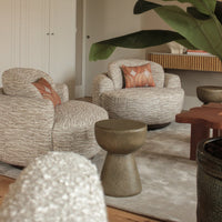 "Neutral textured armchairs with earthy tones and patterned cushions in a stylish modern living space."