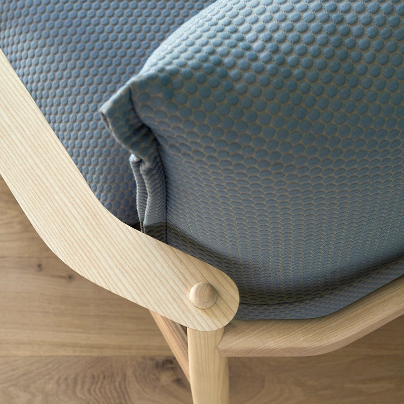 Textured light blue cushion on a natural wood frame, highlighting a minimalist and modern design.