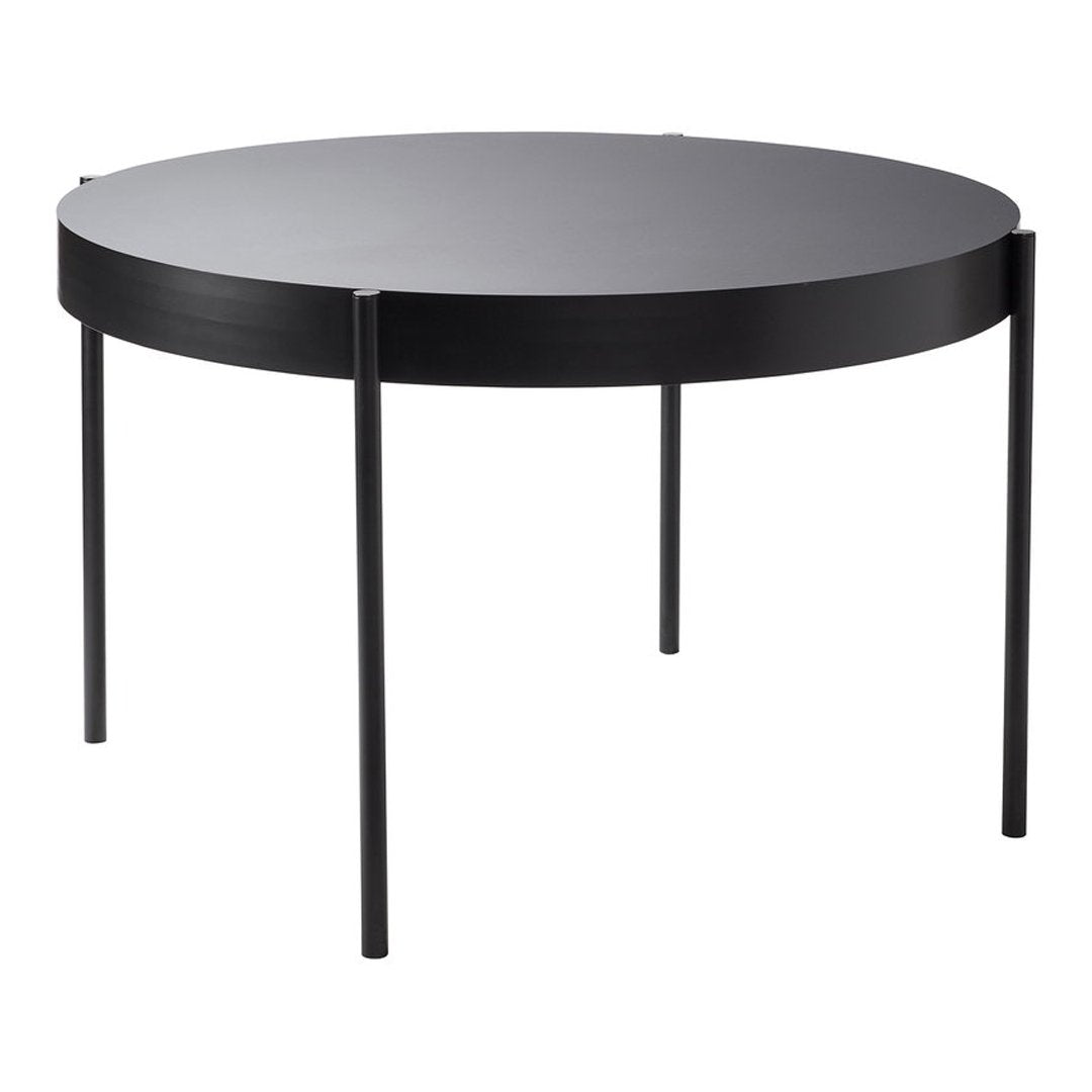 Round black coffee table with a sleek, minimalist design and smooth surface, featuring four slender legs.