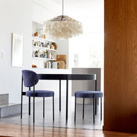 "Modern round dining table with sleek black finish and textured blue velvet chairs in stylish minimalist kitchen setting."