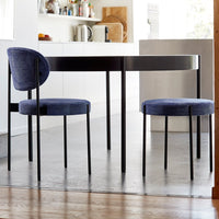 Stylish round table with sleek black finish and modern blue upholstered chairs in a bright, minimalist kitchen setting.