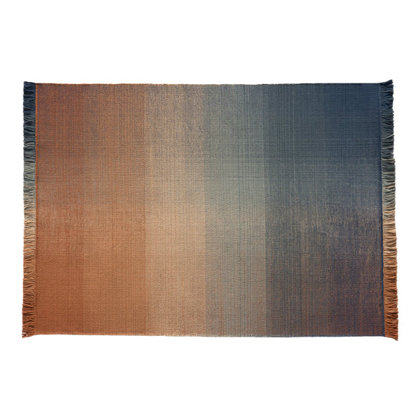 Ombre rug featuring rich gradient hues of rust, orange, and deep blue, with a textured finish and fringed edges.