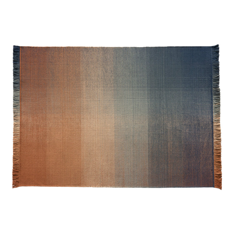 Ombre rug featuring rich gradient hues of rust, orange, and deep blue, with a textured finish and fringed edges.