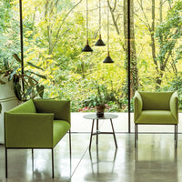 Modern green chairs with sleek black legs, complemented by a glass table in a bright, nature-inspired setting.