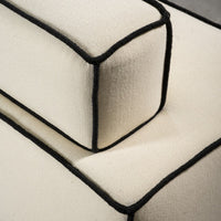 Ivory fabric with contrasting black piping, showcasing a sleek, modern design and textured surface details.