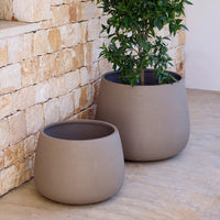 Set of two textured, circular pots in soft taupe, perfect for indoor or outdoor plants. Elegant, minimalist design.