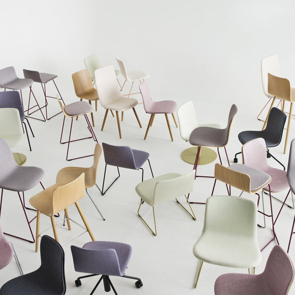 Variety of chairs in soft pastels, including lavender, mint green, beige, and grey, with wooden and metal legs.