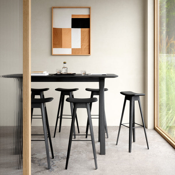 Black bar stools around a sleek black table, with a modern geometric artwork featuring gold, white, and black colors.