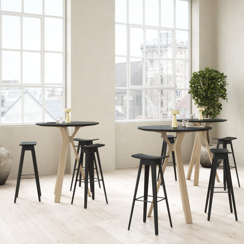Stylish black and natural wood bar table set with sleek, modern design in a bright, airy space.
