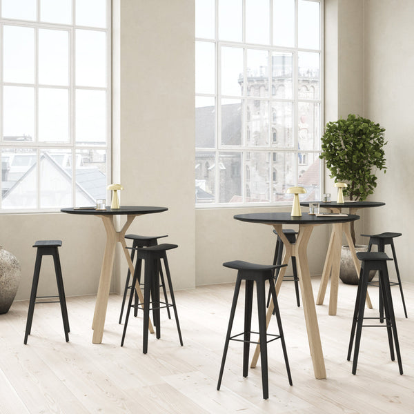 Black and natural wood bar tables with matching stools in a bright, airy space. Modern design with minimalistic patterns.