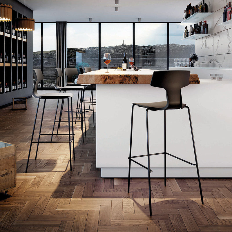 Black bar stool against a modern kitchen backdrop with white cabinetry and warm wooden flooring.