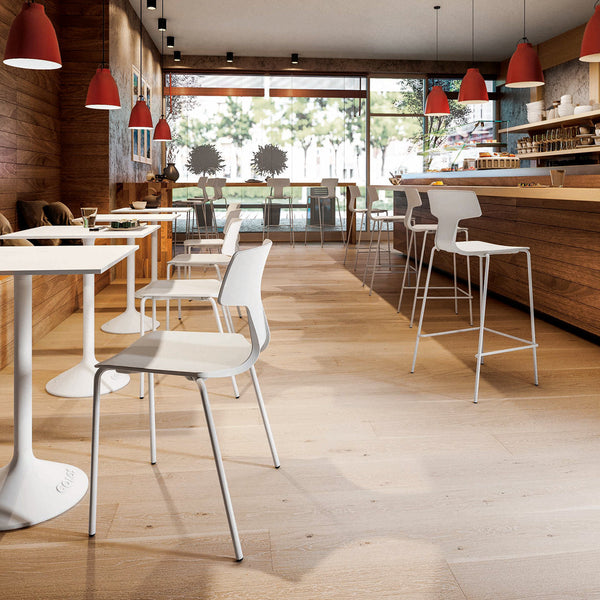 Modern cafe interior with white chairs, light wood flooring, and red pendant lights. Clean and minimal design.