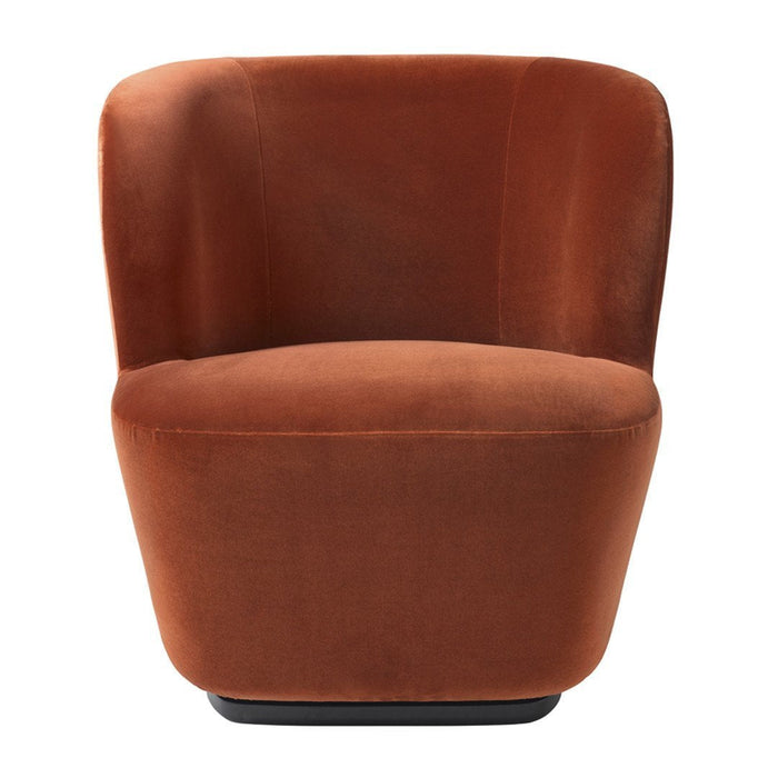 Rust orange velvet chair with a smooth, curved design and no visible patterns, enhancing modern decor.