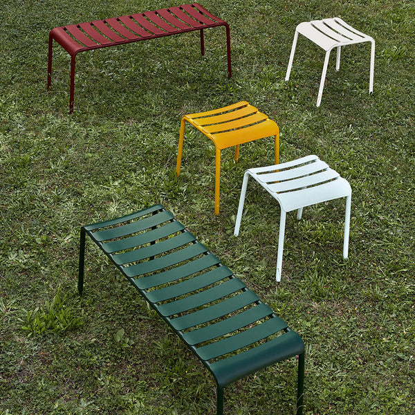 Colorful metal benches in red, yellow, green, white, and striped pattern on green grass background.