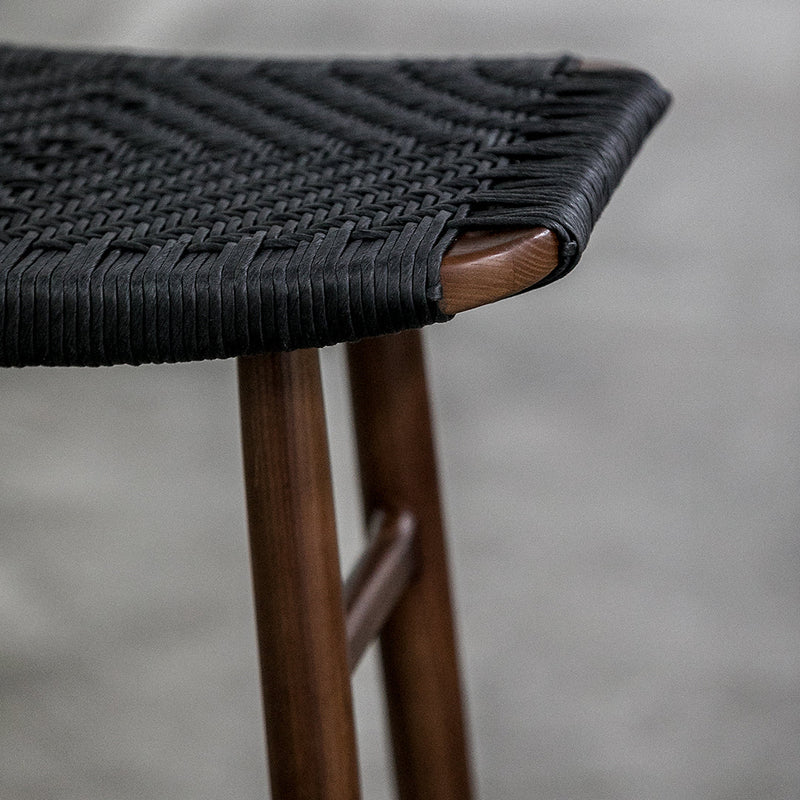 Black woven seat with intricate texture, paired with warm wooden legs, creating a stylish contrast.