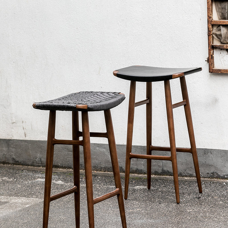 Black woven bar stools with natural wood legs, featuring sleek, modern design and textured patterns.