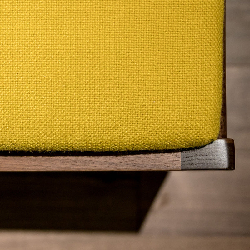 Yellow textured fabric on a modern wooden surface, showcasing vibrant color and subtle pattern contrast.