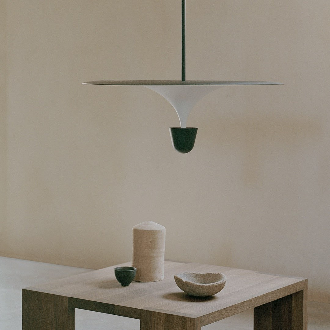 Modern pendant lamp in white and green, showcasing minimalist design against a soft beige backdrop.