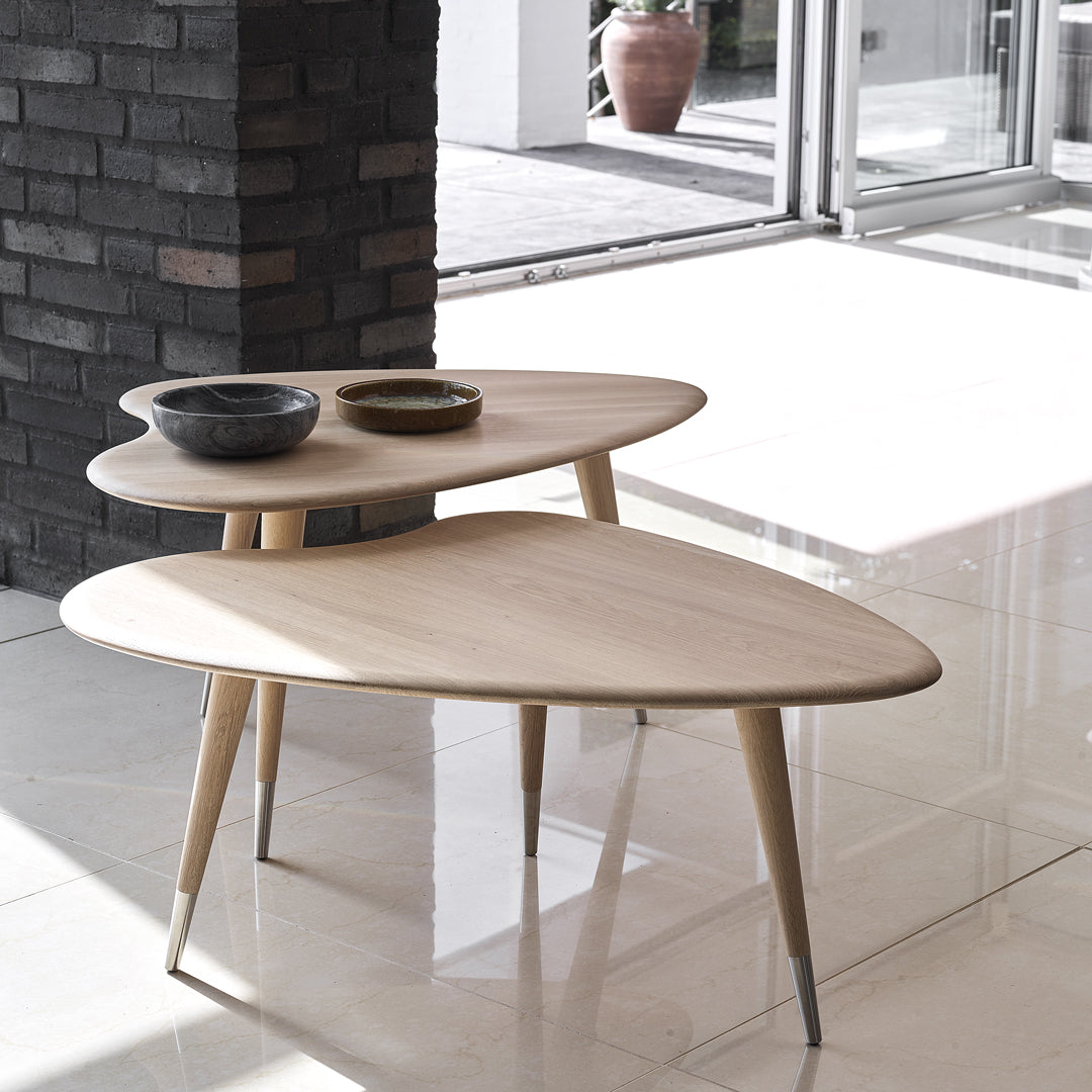 Light wood coffee table with a smooth, organic shape and natural finish, featuring minimalist design and warm, neutral tones.