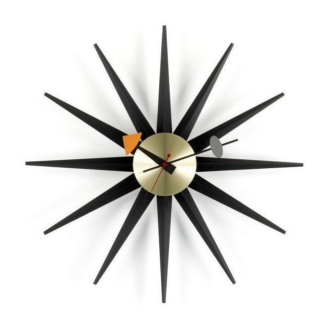 Retro starburst wall clock in black and gold with orange and gray accents. Modern design with sharp, angular patterns.