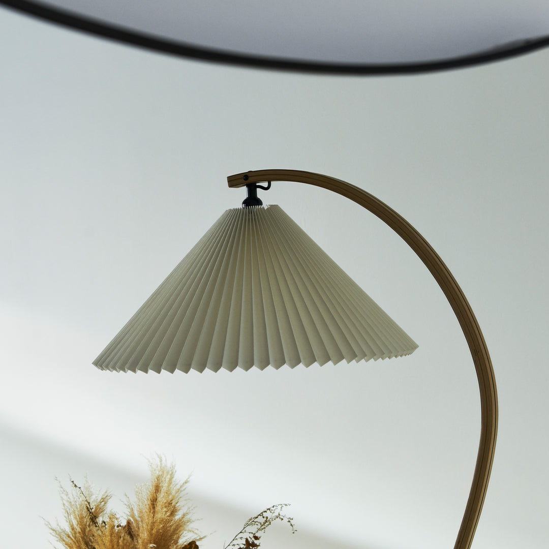 Off-white pleated lamp shade with a curved wooden base; elegant and modern design. Perfect for minimalist decor.