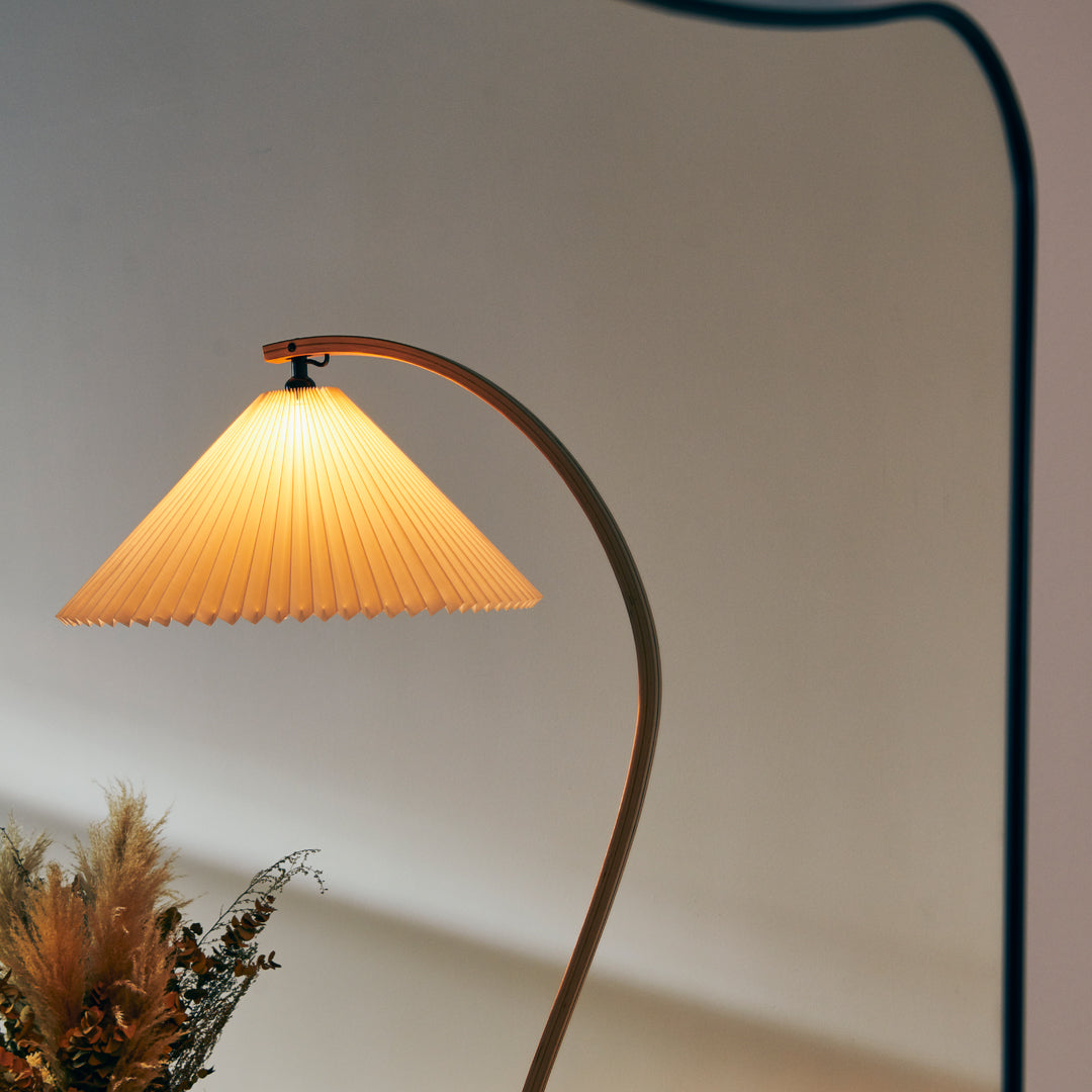 Warm yellow pleated lampshade with a sleek curved base, enhancing modern decor with soft illumination.