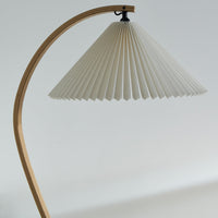 White pleated lampshade with natural wood curved base, creating a minimalist and elegant design.